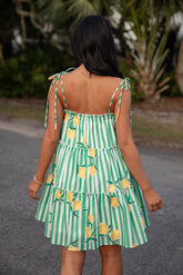 Person wearing a green and white striped dress with lemon patterns outdoors.