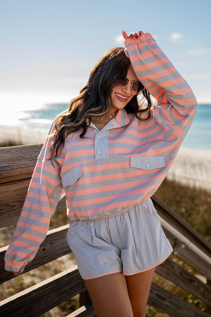 Woman wearing a striped shirt and shorts by the beach