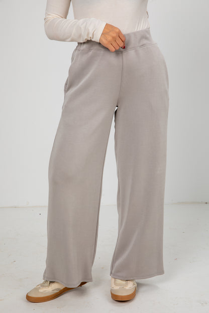 Person wearing light gray wide-leg pants on a white background