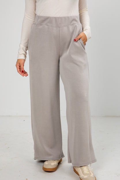 Person wearing light gray wide-leg pants on a white background