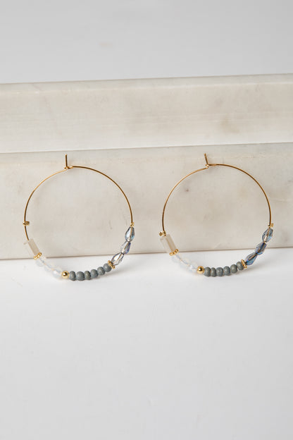 Gold hoop earrings with beaded accents on a light surface