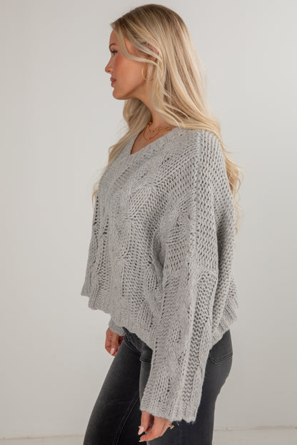 Woman wearing a gray knitted sweater against a white background