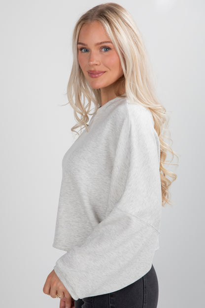 Woman wearing a light gray sweater against a white background