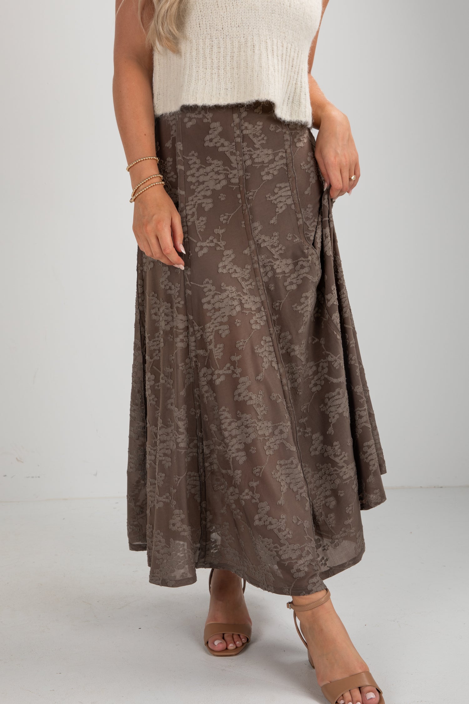Person wearing a brown floral skirt on a plain background
