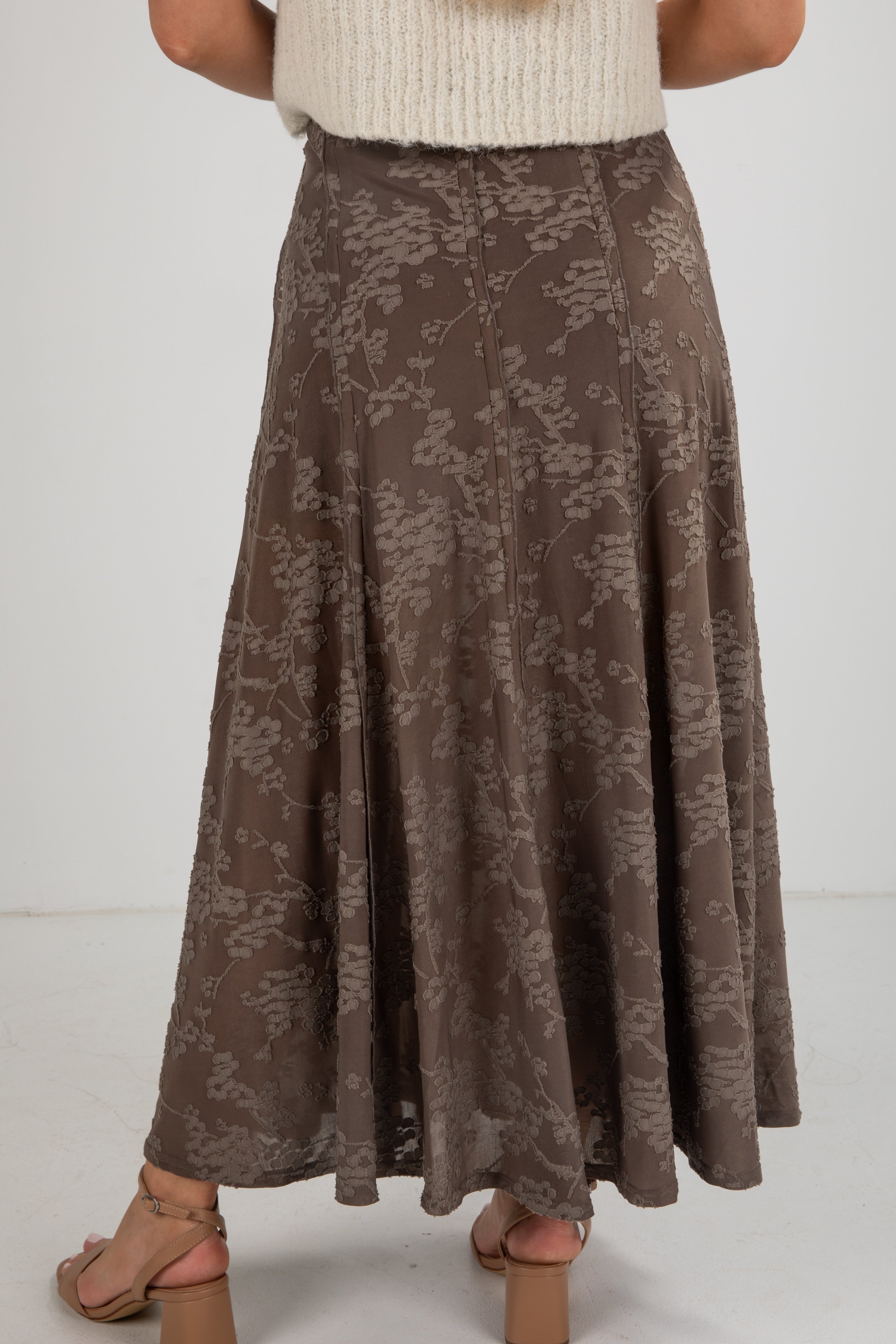 Brown floral patterned skirt worn by a person on a white background
