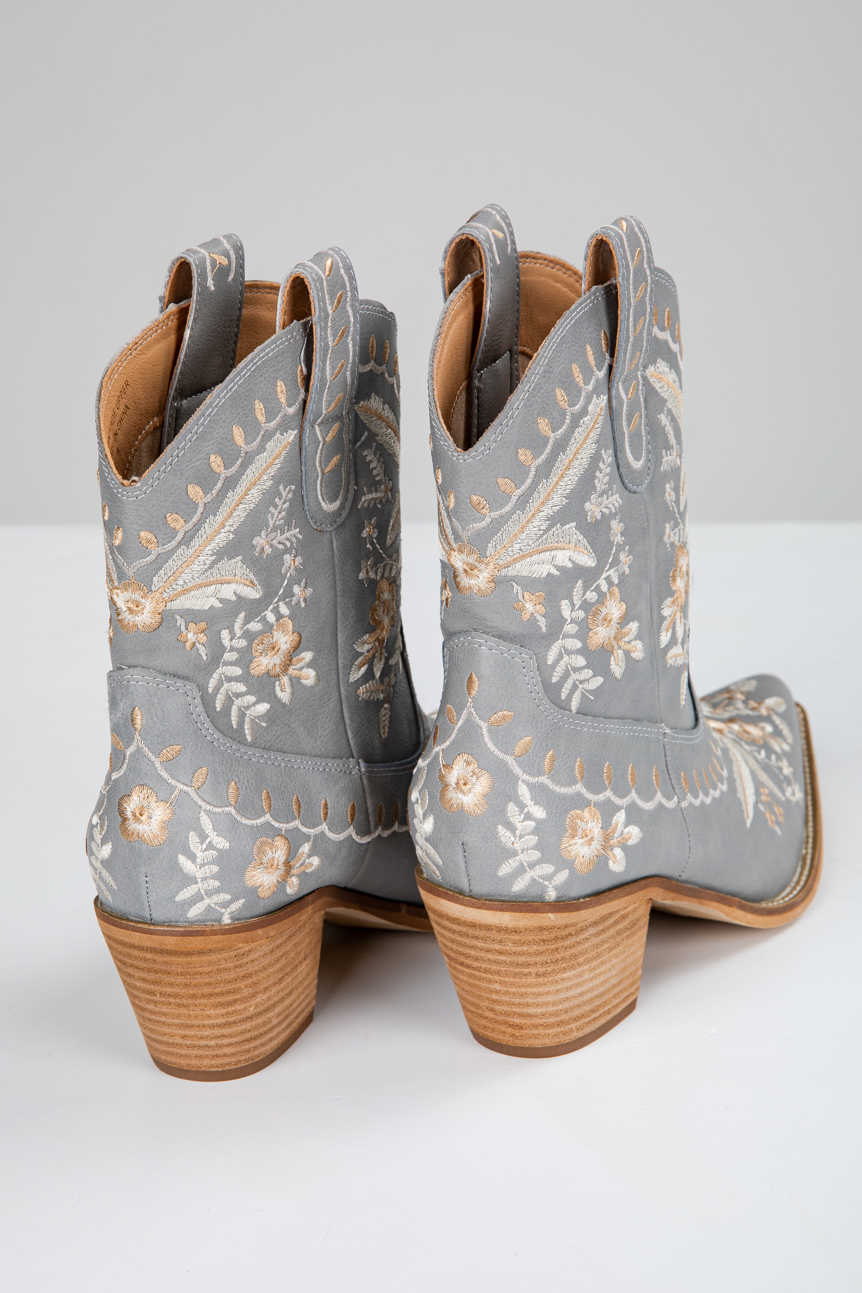 Gray cowboy boots with floral embroidery on a white background