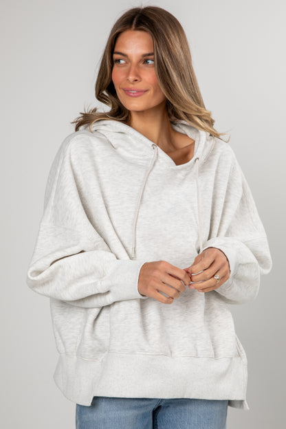 Woman wearing a white hoodie against a plain background