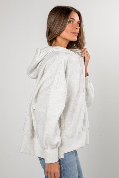 Woman wearing a light gray hoodie against a plain background