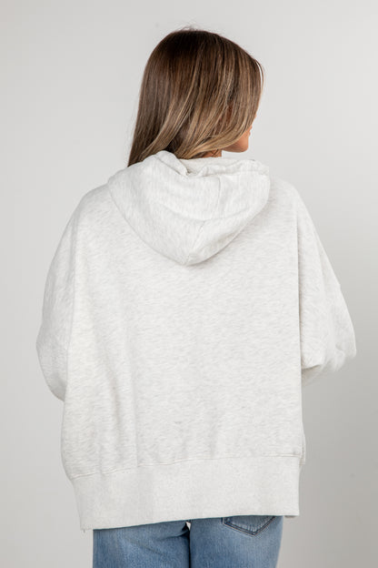 Person wearing a light gray hoodie from behind on a plain background