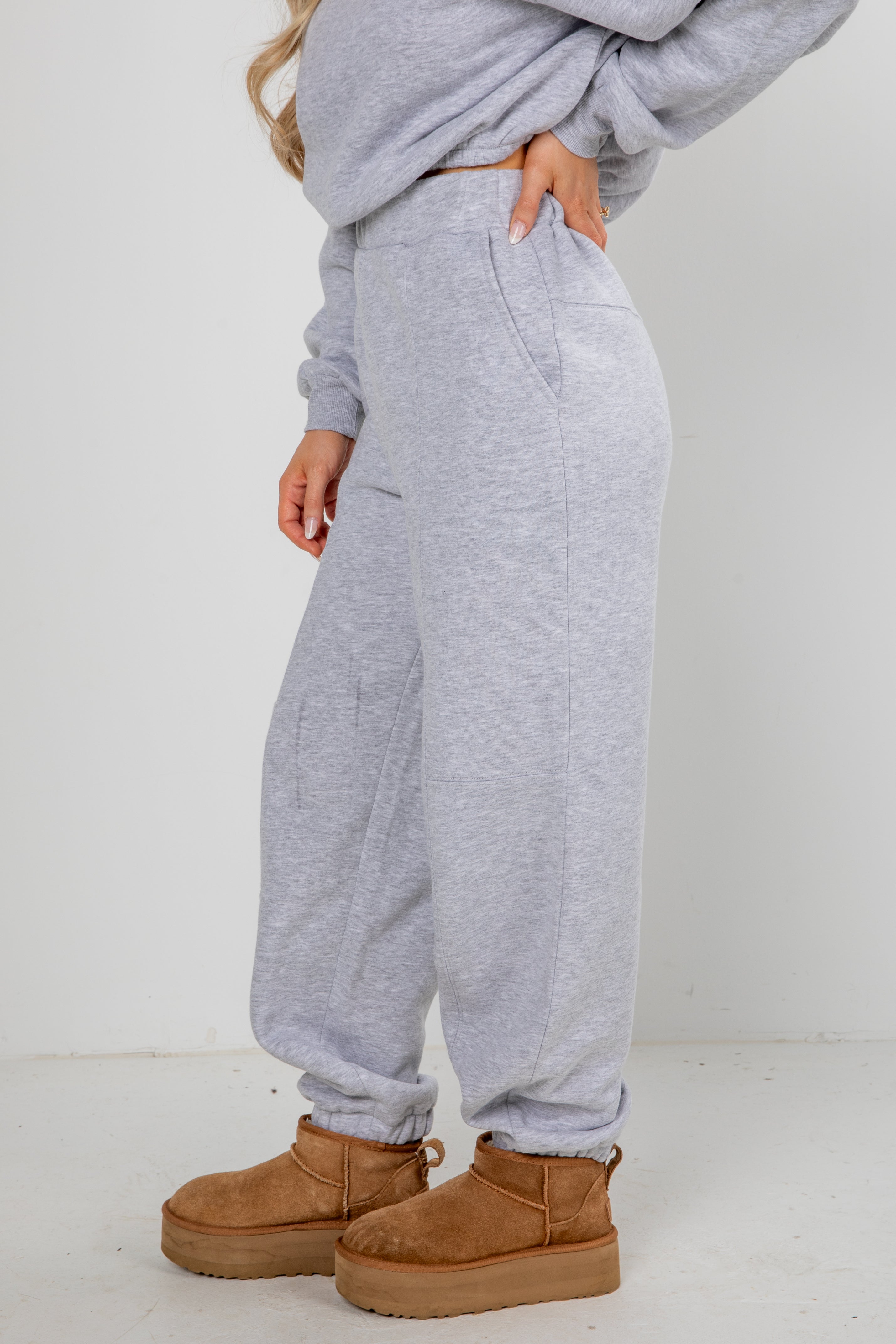 Person wearing gray sweatpants and brown boots on a white background