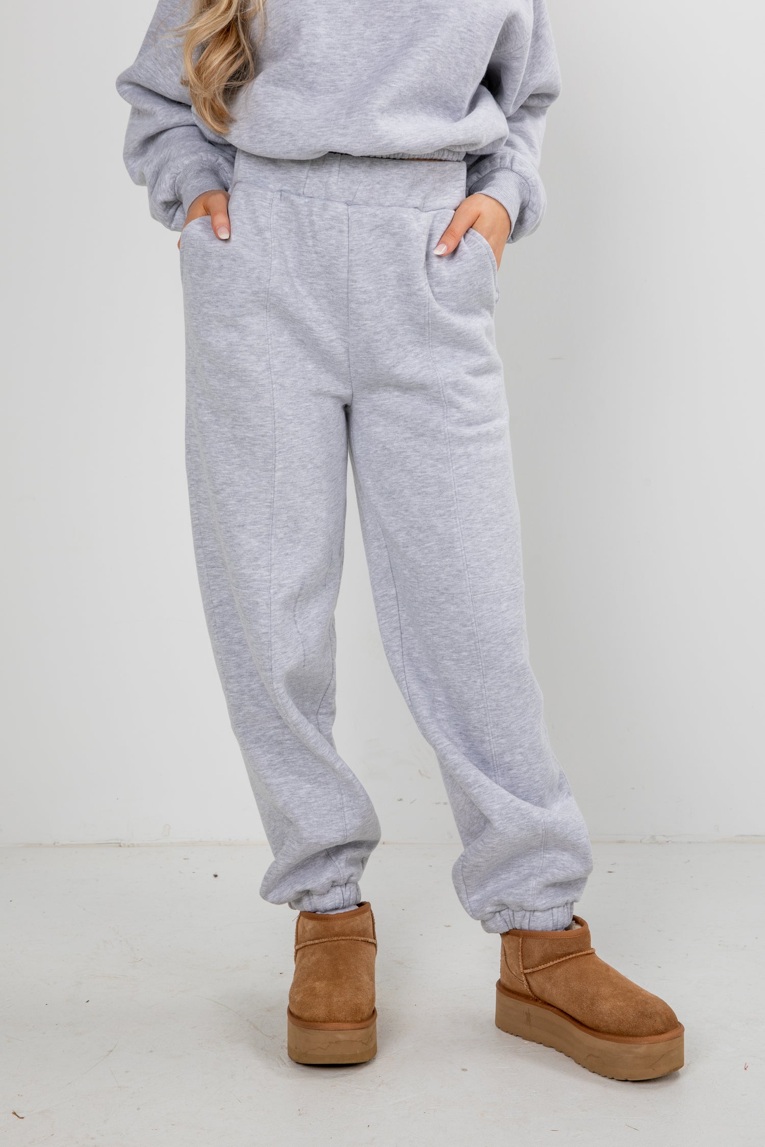 Person wearing gray sweatpants and brown boots on a white background