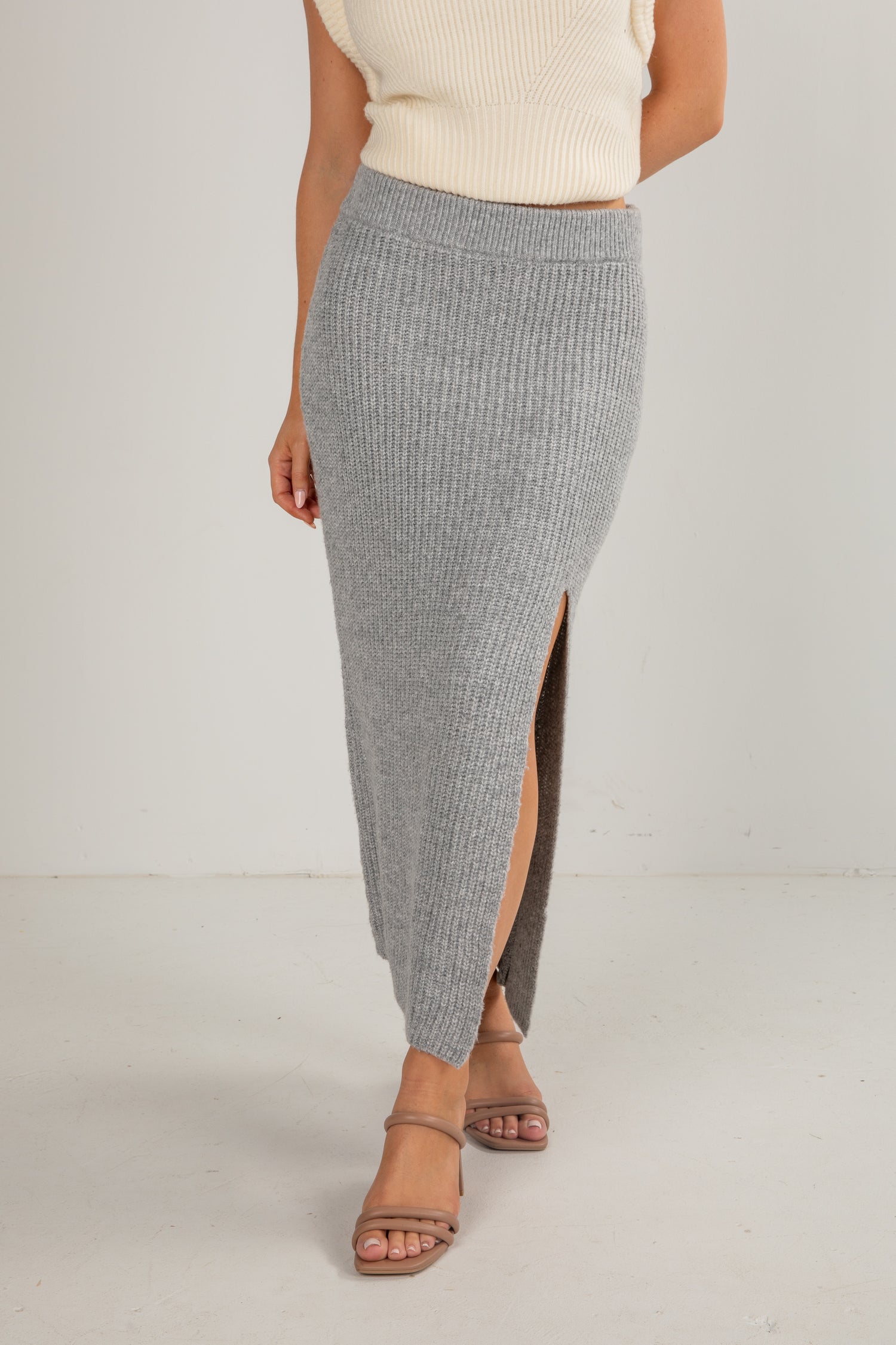 Person wearing a gray ribbed skirt with a white background