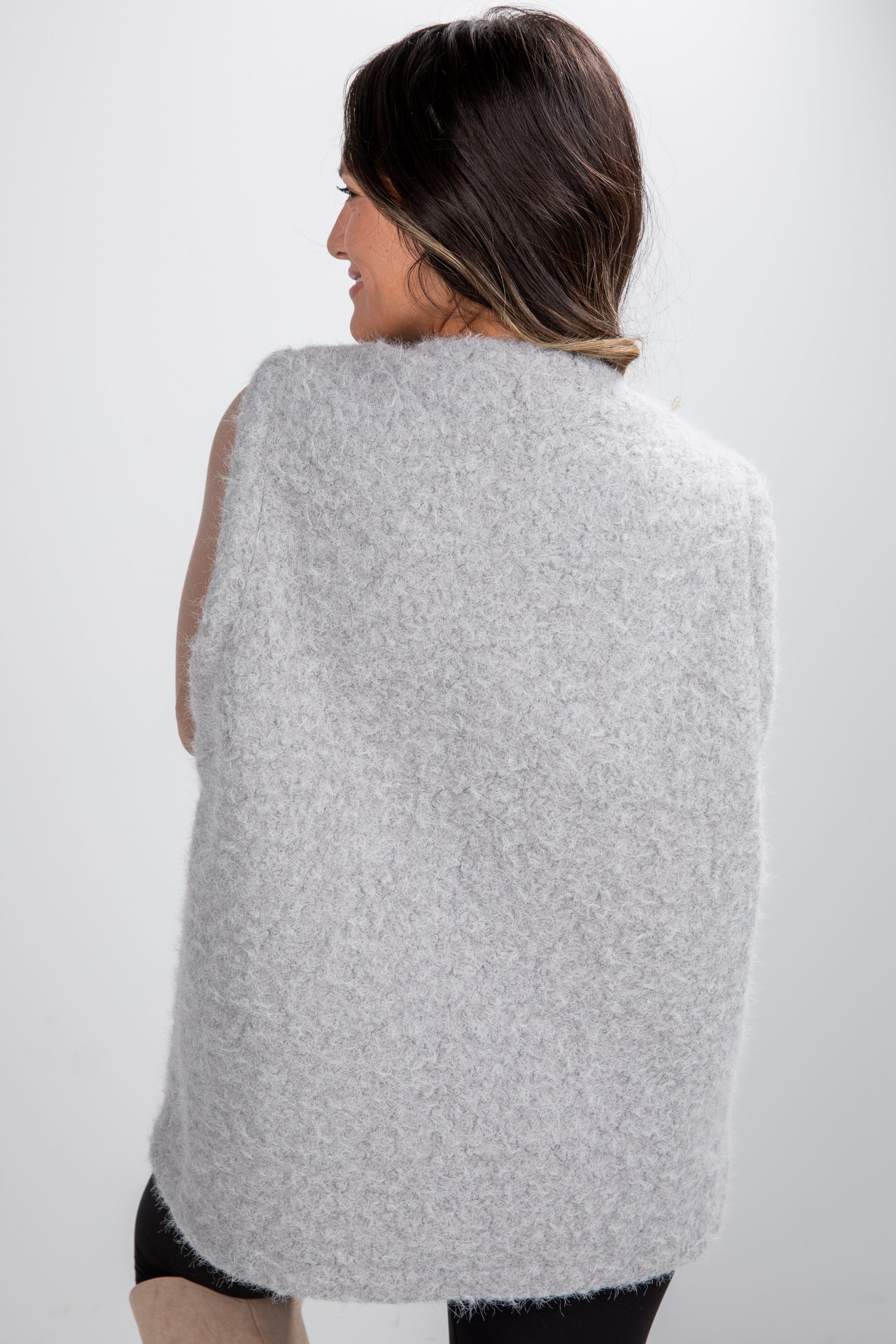 Woman wearing a gray poncho against a white background