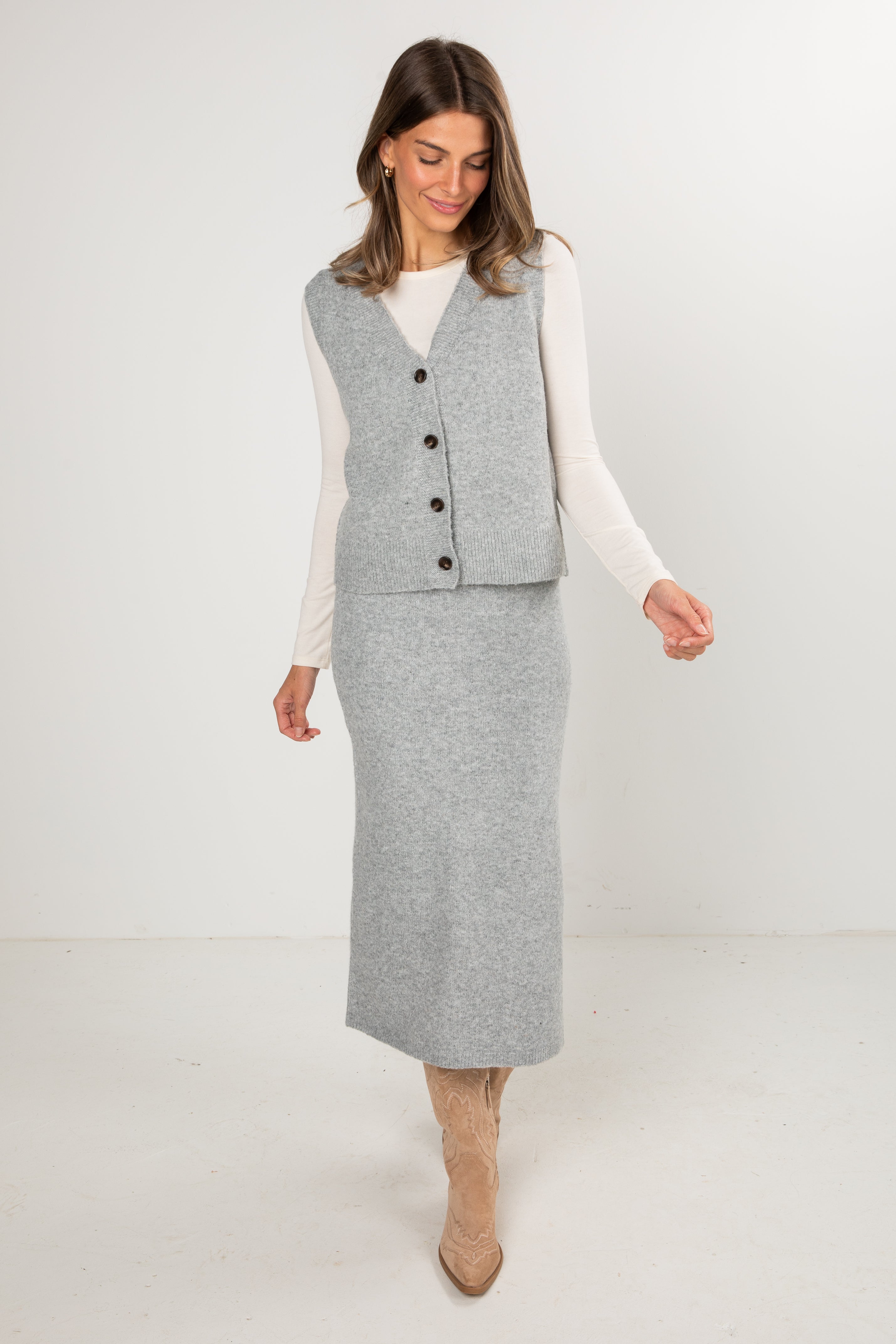 Woman wearing a gray vest and skirt set on a white background