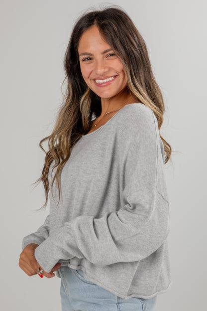 Woman wearing a gray sweater against a plain background