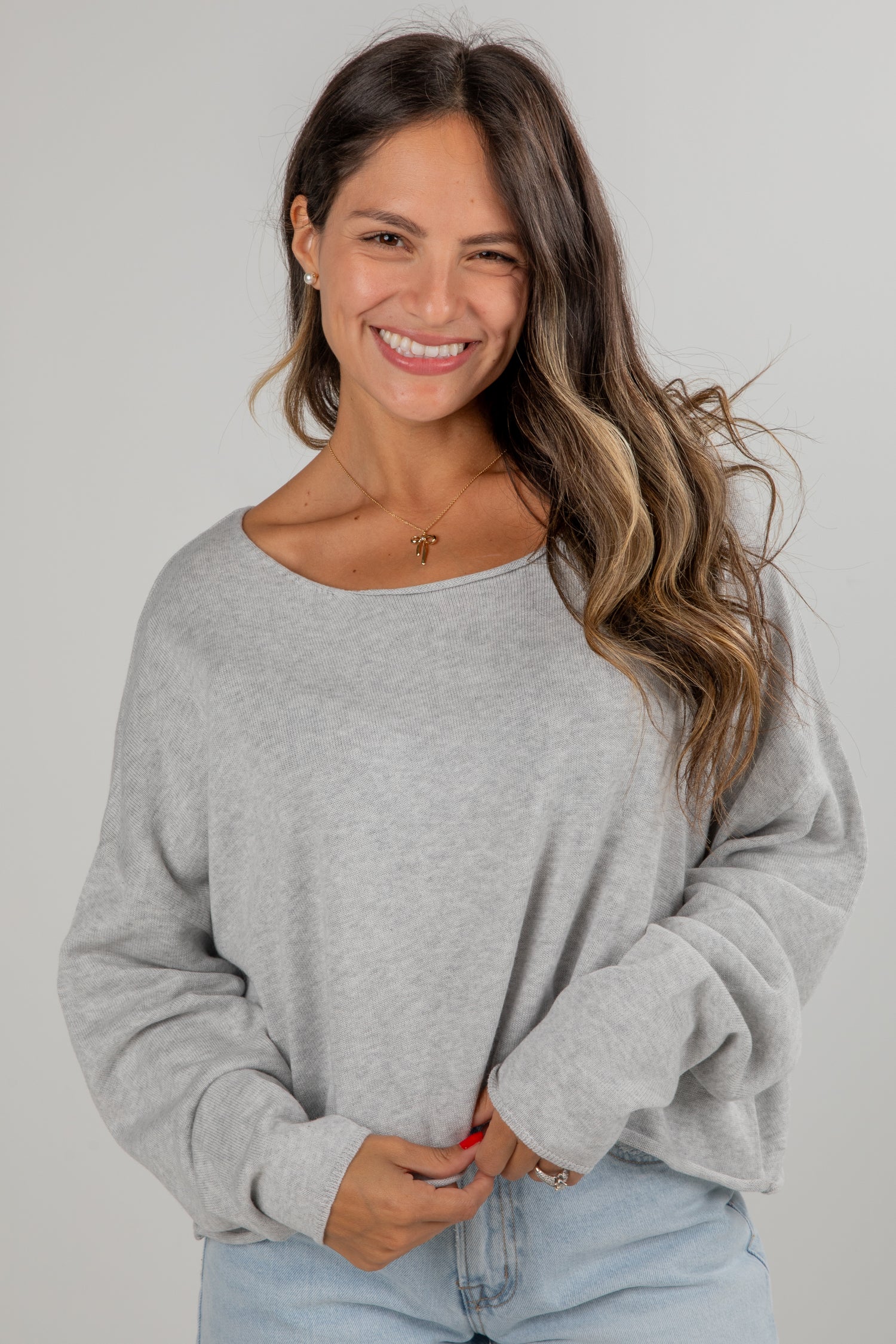 Woman wearing a gray sweater against a plain background