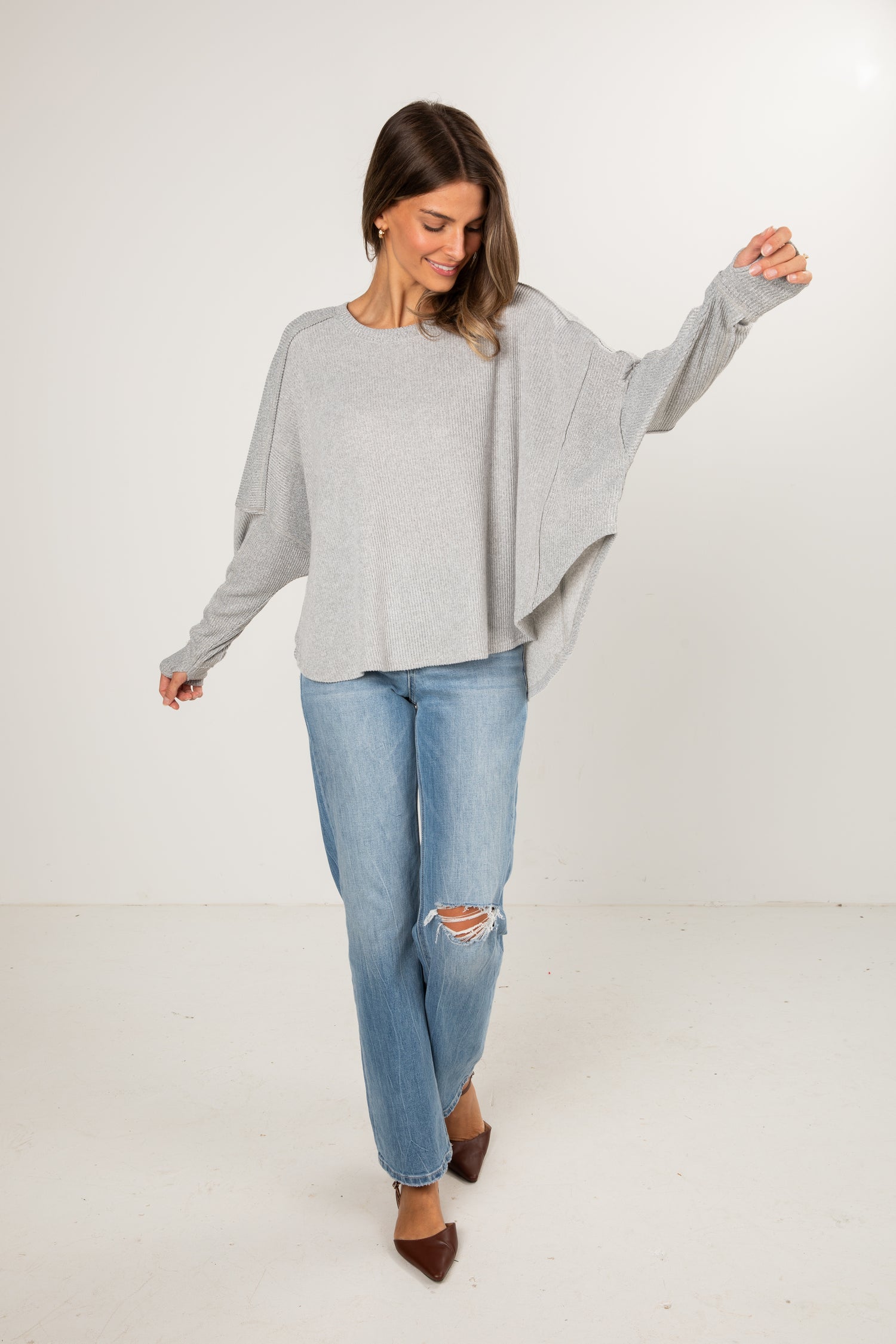 Woman wearing a gray sweater and blue jeans on a white background