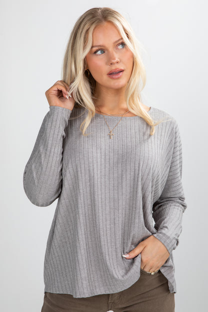 Woman wearing a gray ribbed sweater against a white background