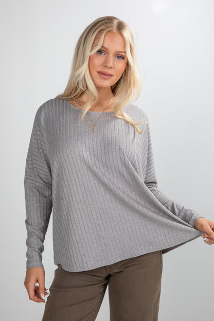 Woman wearing a gray ribbed sweater and brown pants against a white background