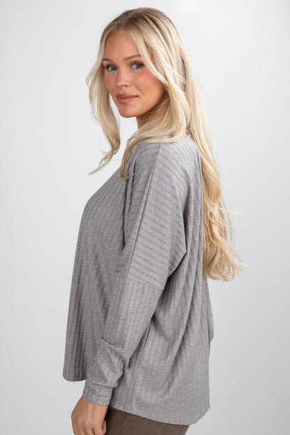 Woman wearing a gray ribbed sweater against a plain background