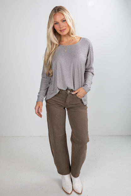 Woman wearing a gray sweater and brown pants on a white background