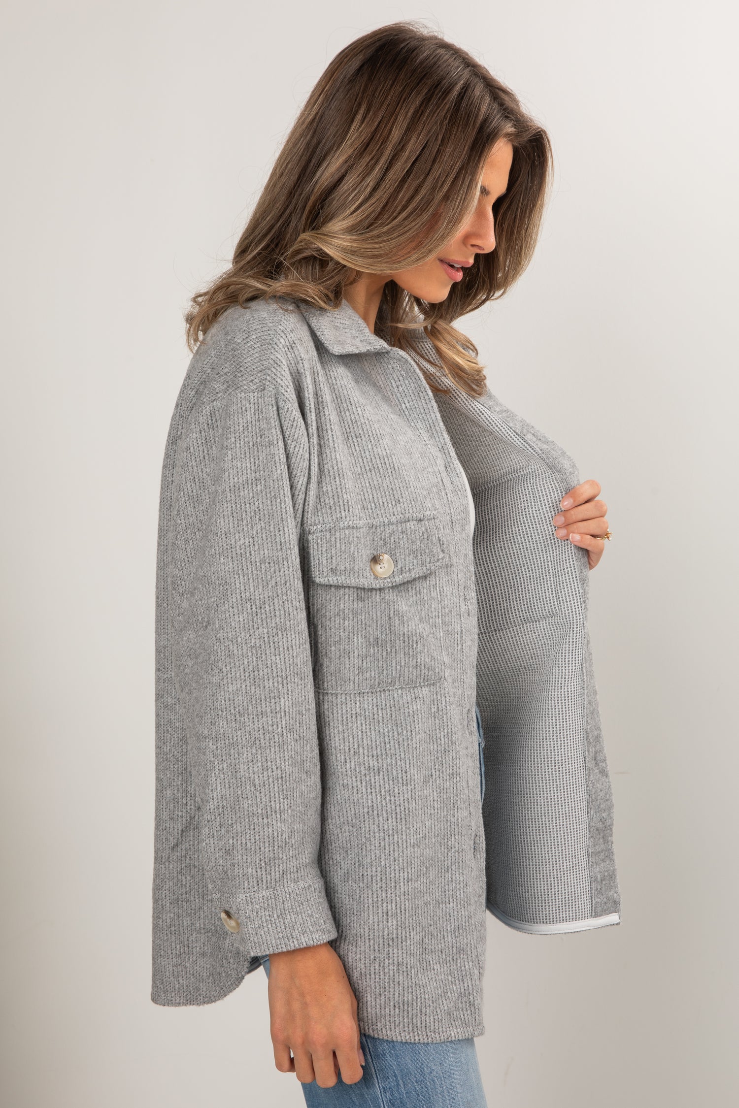 Woman wearing a gray checkered coat against a plain background