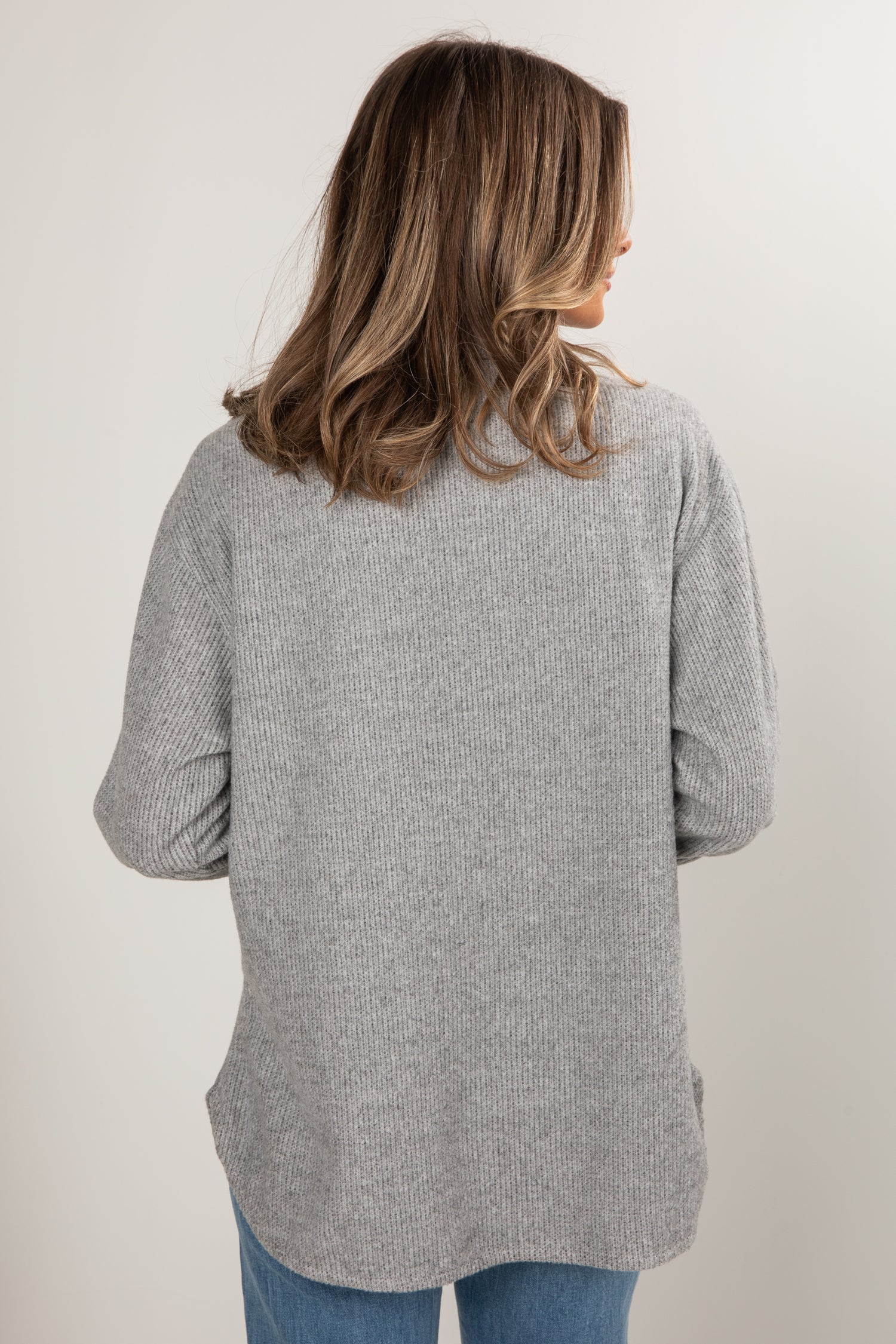 Person wearing a gray cardigan against a white background