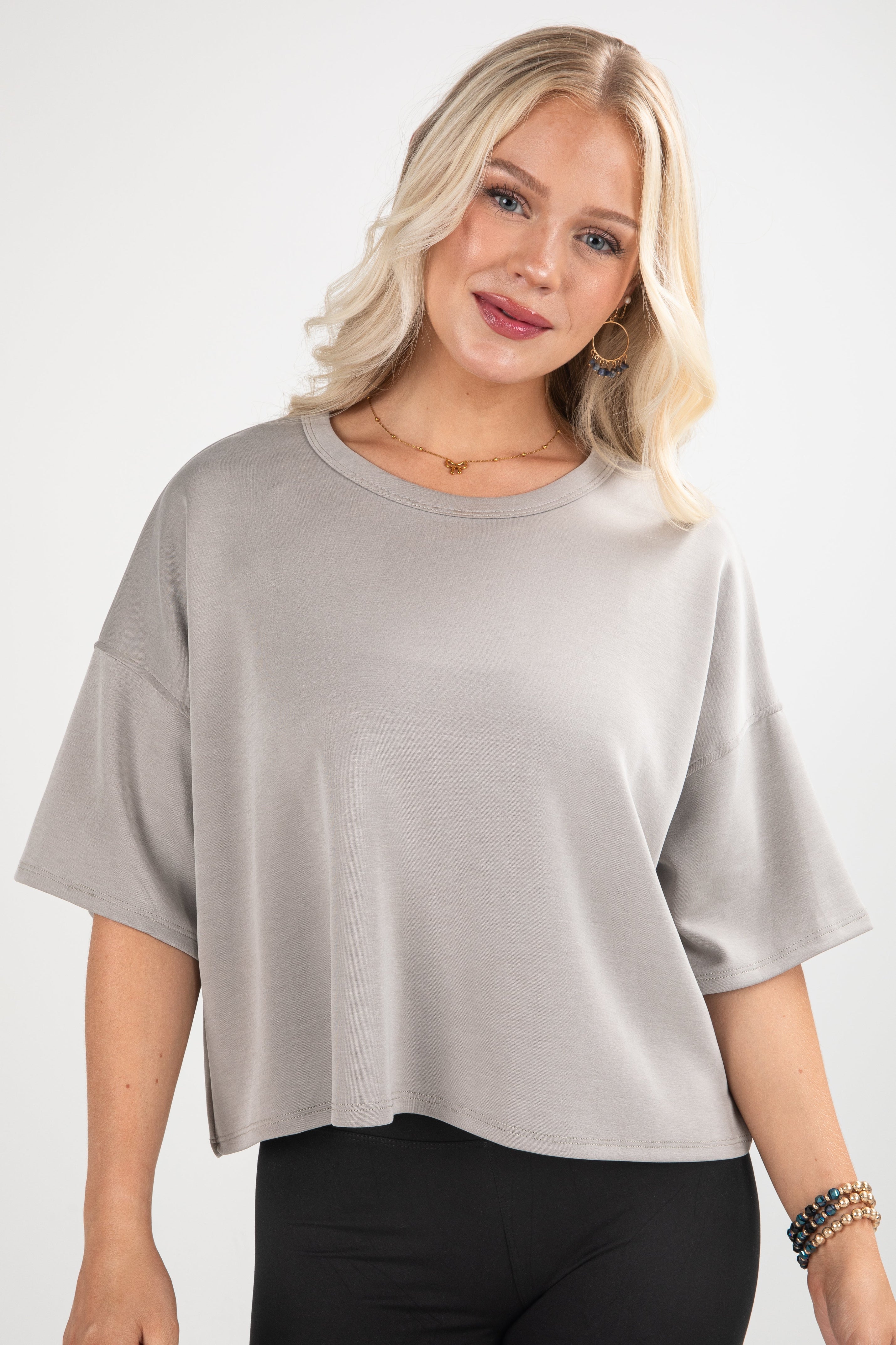 Woman wearing a light gray oversized shirt on a white background
