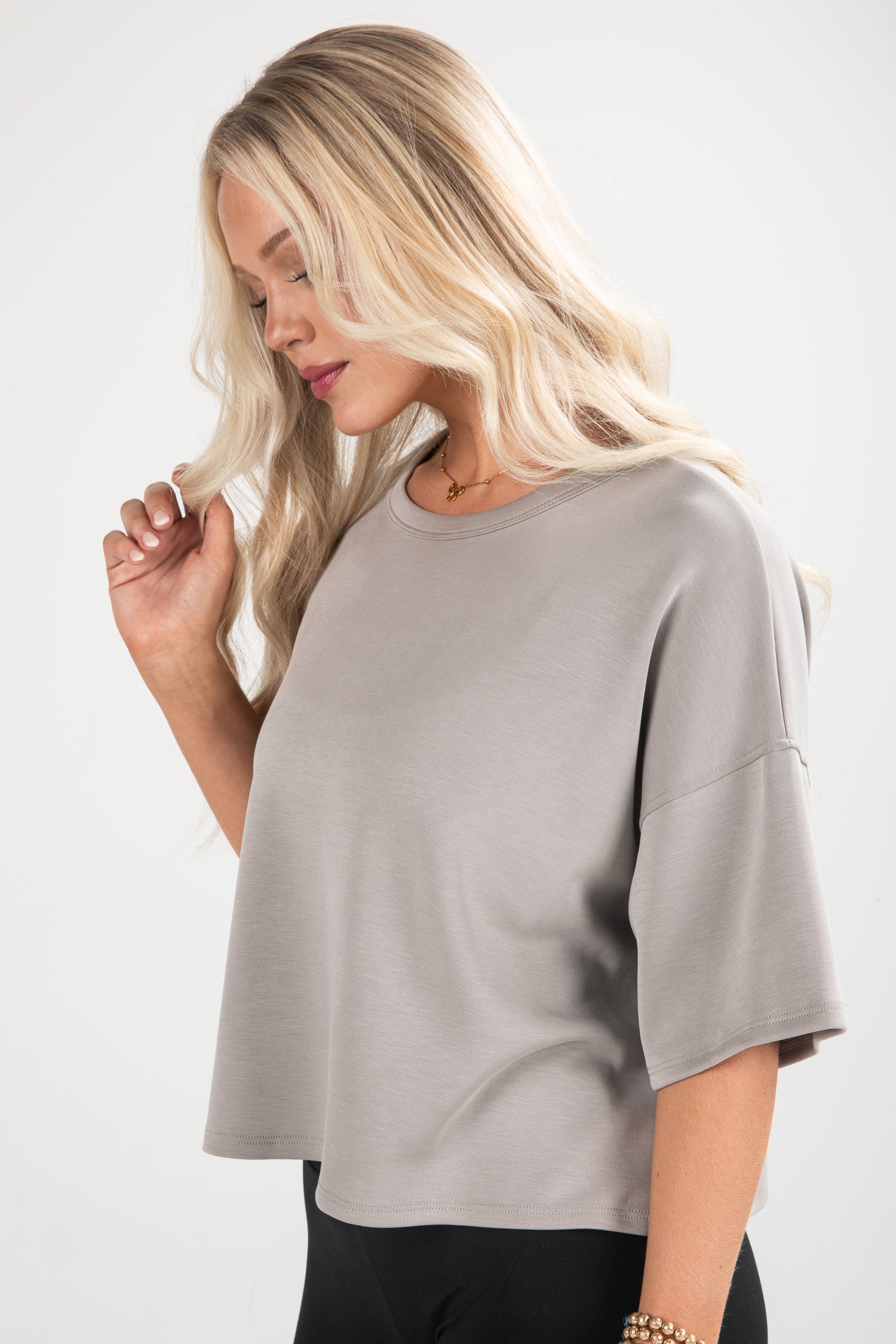 Woman wearing a gray oversized top against a white background