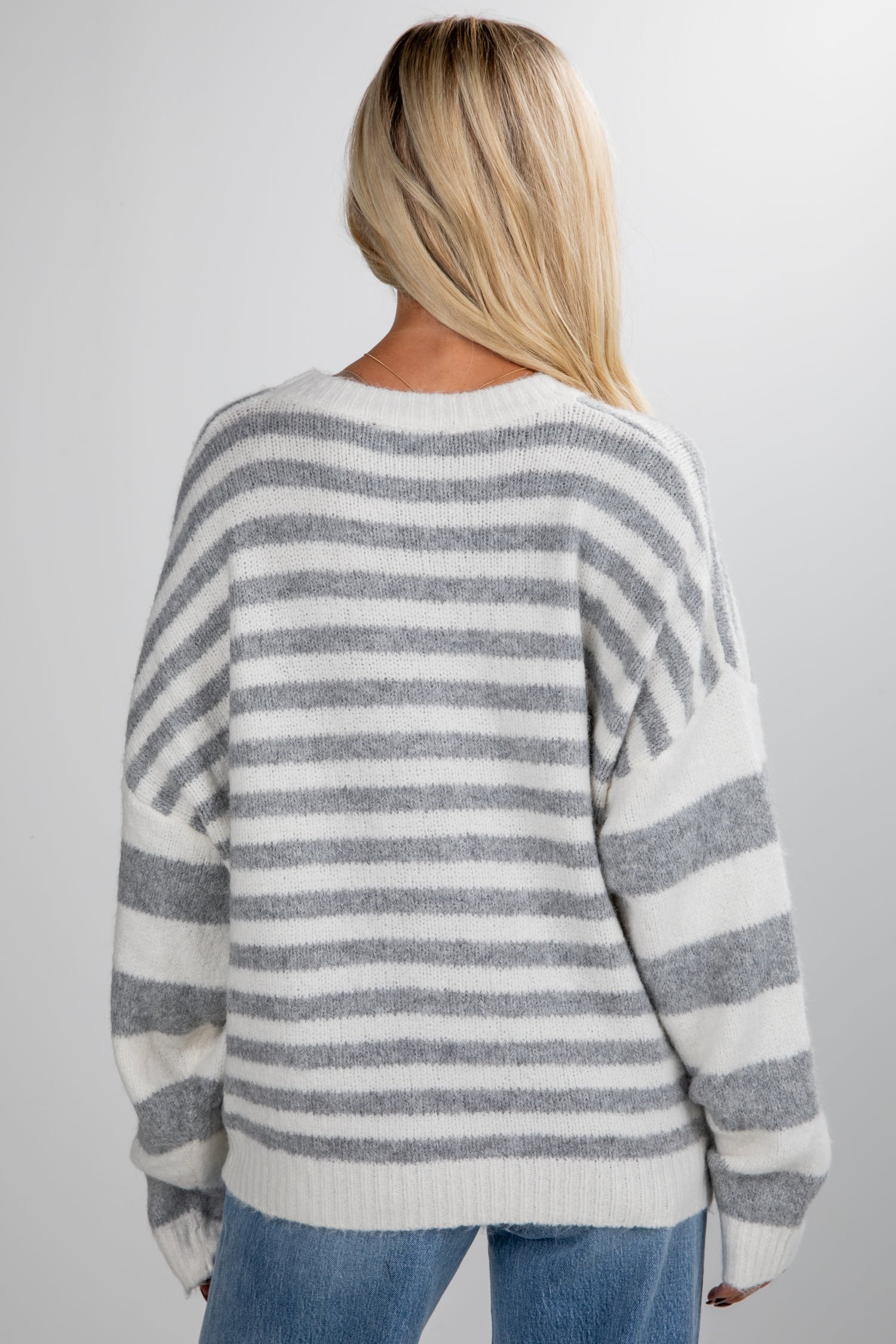 Person wearing a gray and white striped sweater on a plain background