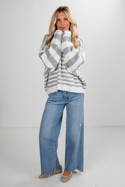 Woman wearing a striped sweater and jeans on a white background