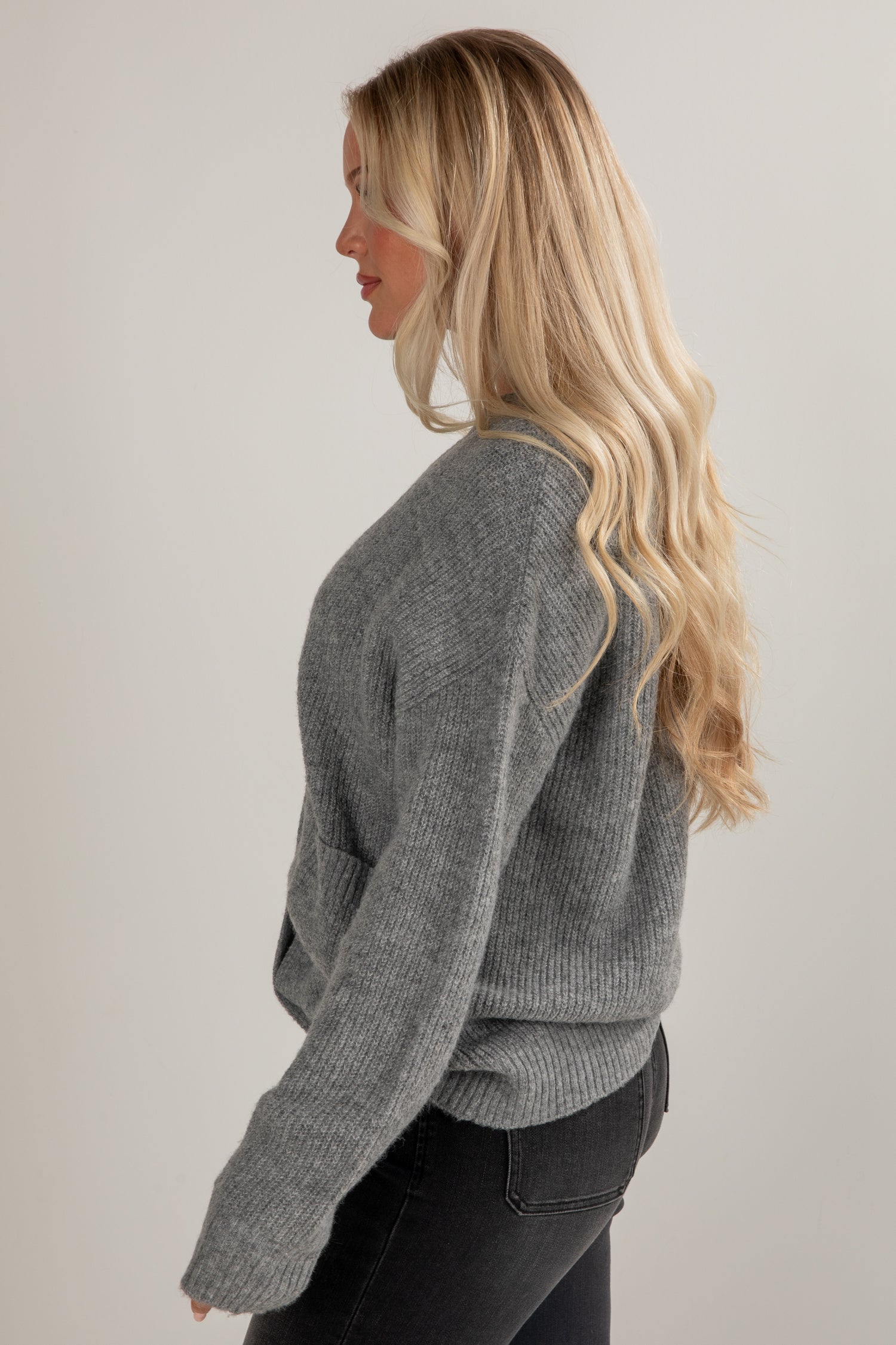 Woman wearing a gray sweater against a plain background