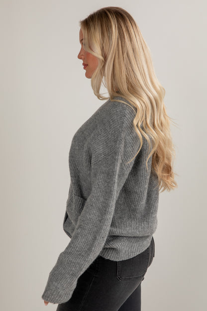Woman wearing a gray sweater against a plain background