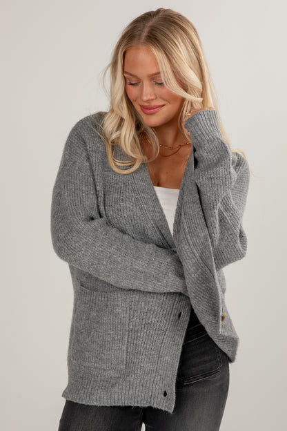 Woman wearing a gray cardigan against a plain background