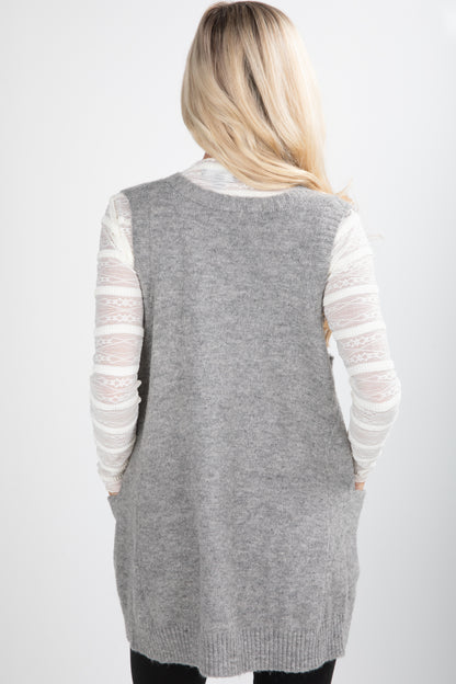 Person wearing a gray cardigan over a white long-sleeve shirt on a white background