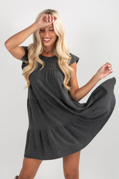 Woman wearing a dark gray dress against a plain background