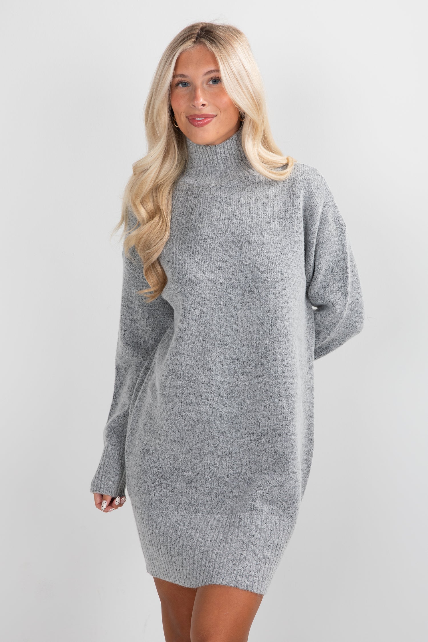 Woman wearing a gray sweater dress against a white background