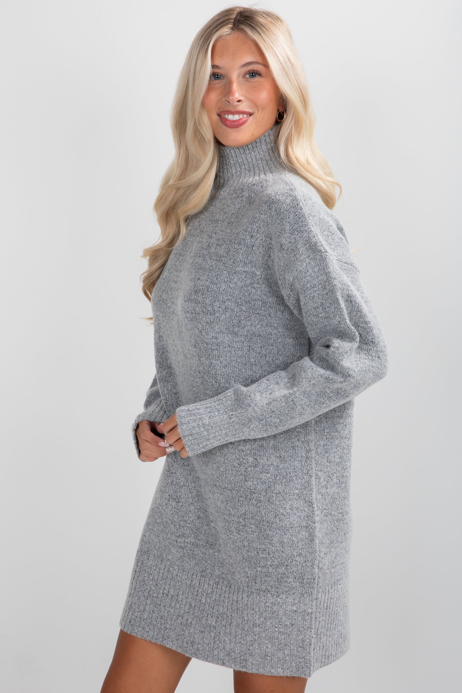 Woman wearing a gray sweater dress against a plain background