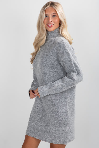 Woman wearing a gray sweater dress against a plain background