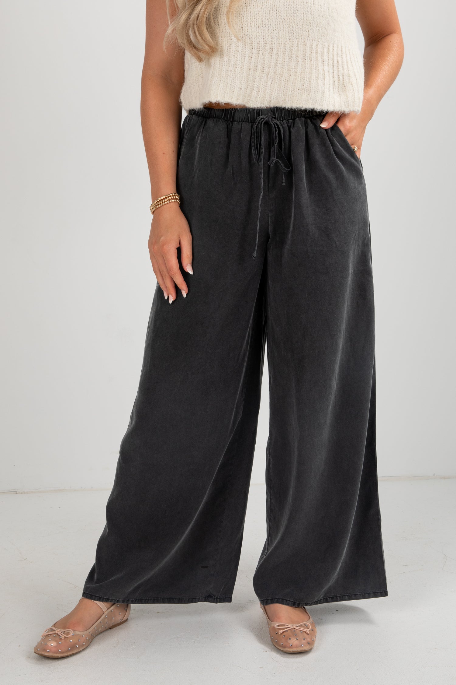 Person wearing black wide-leg pants with a white background