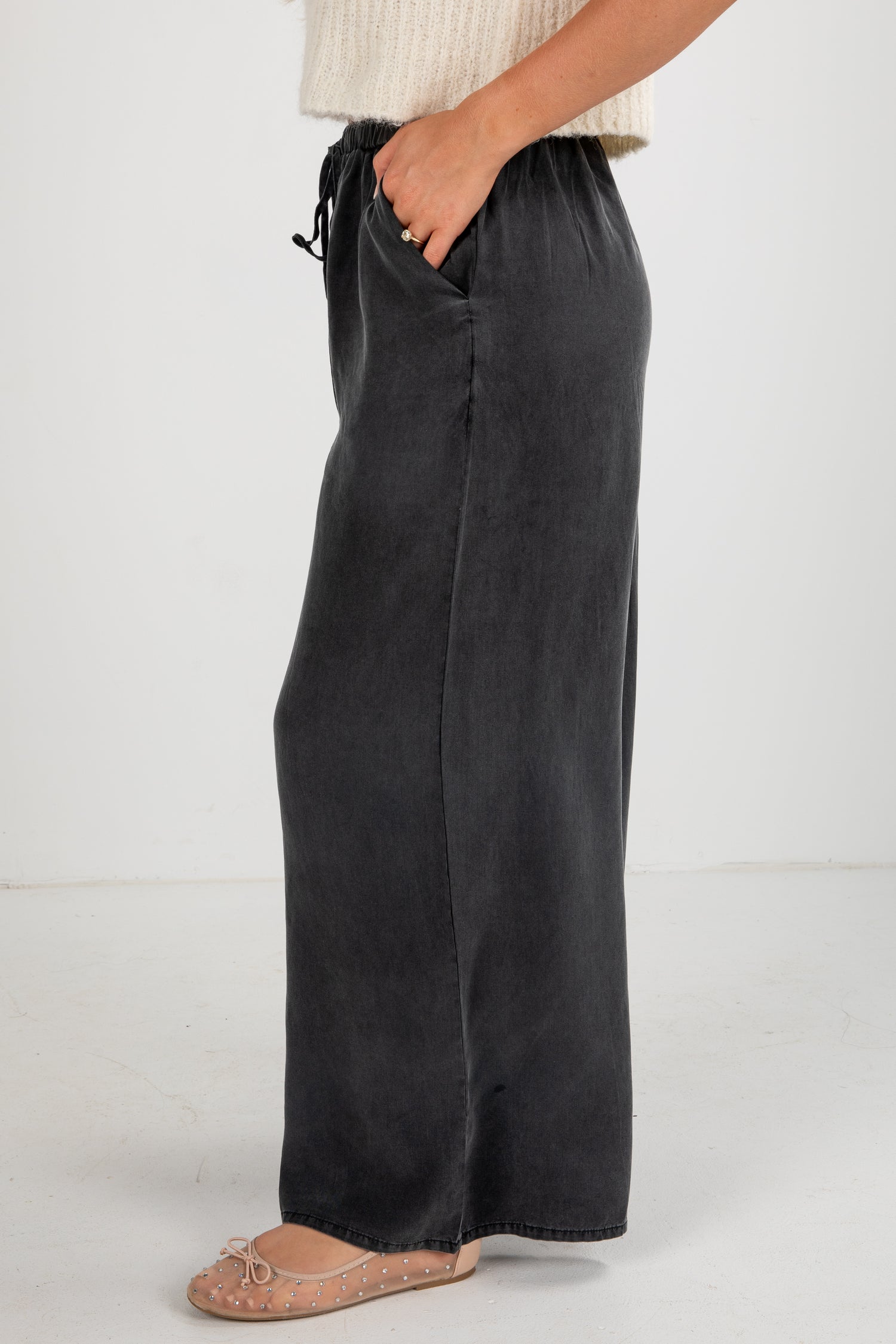 Person wearing black wide-leg pants on a white background