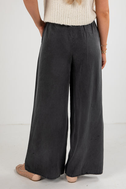 Person wearing black wide-leg pants on a white background