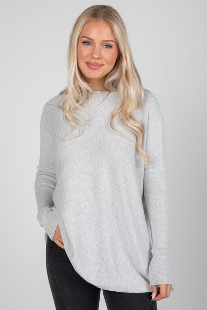 Woman wearing a light gray sweater against a plain background