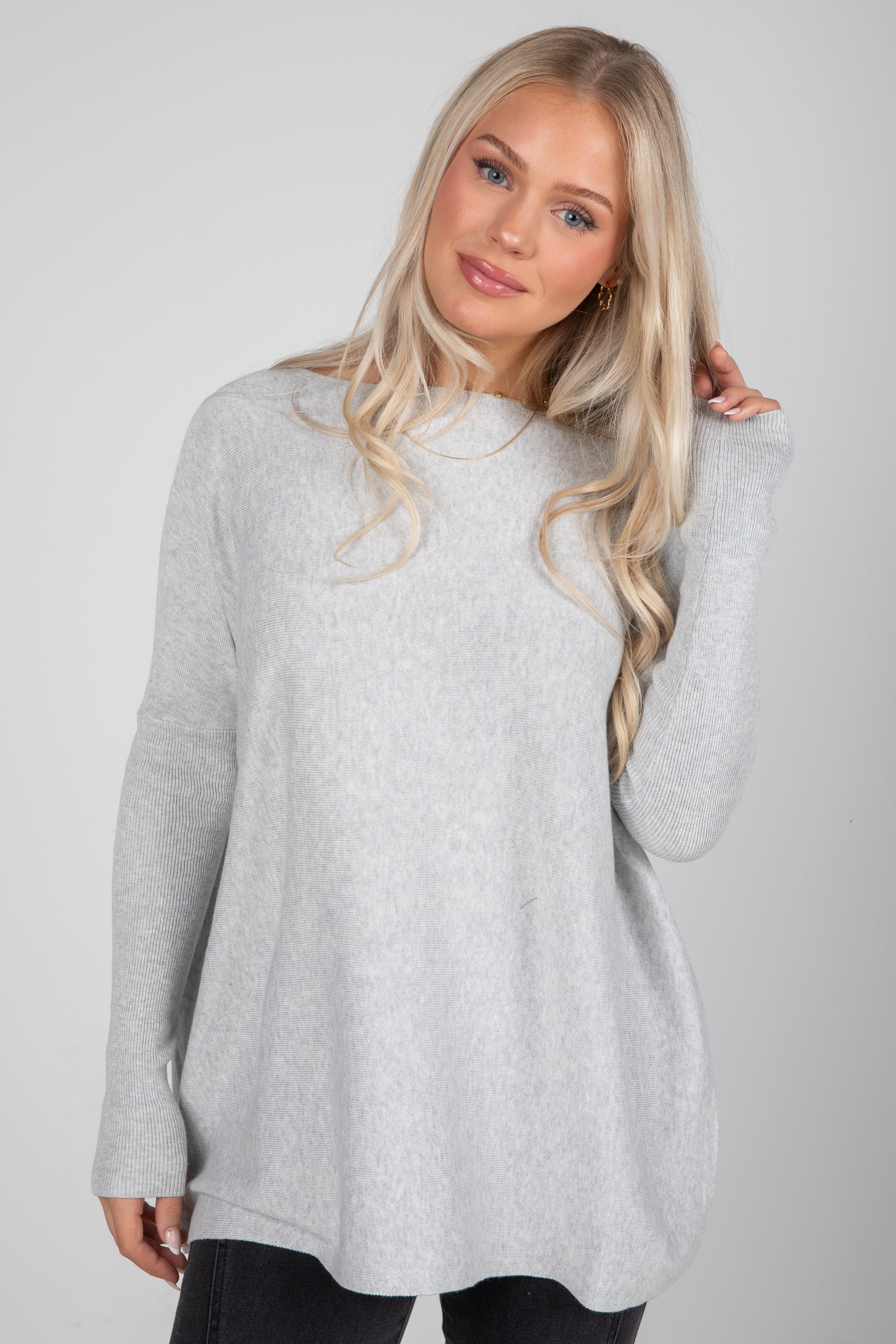 Woman wearing a gray sweater against a plain background