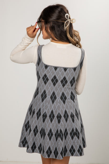 Woman wearing a gray and black diamond patterned dress against a white background