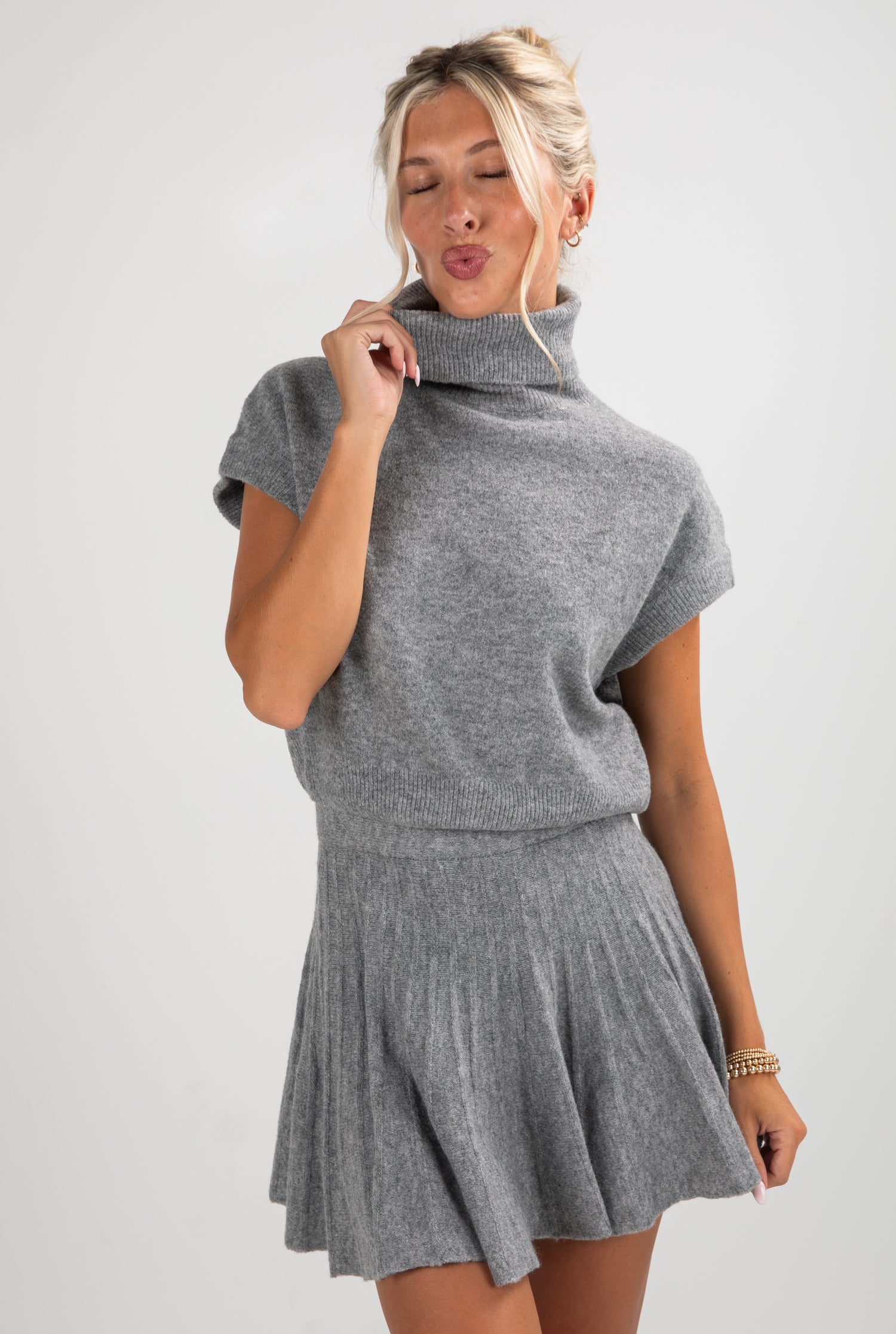 Woman wearing a gray knit dress against a white background