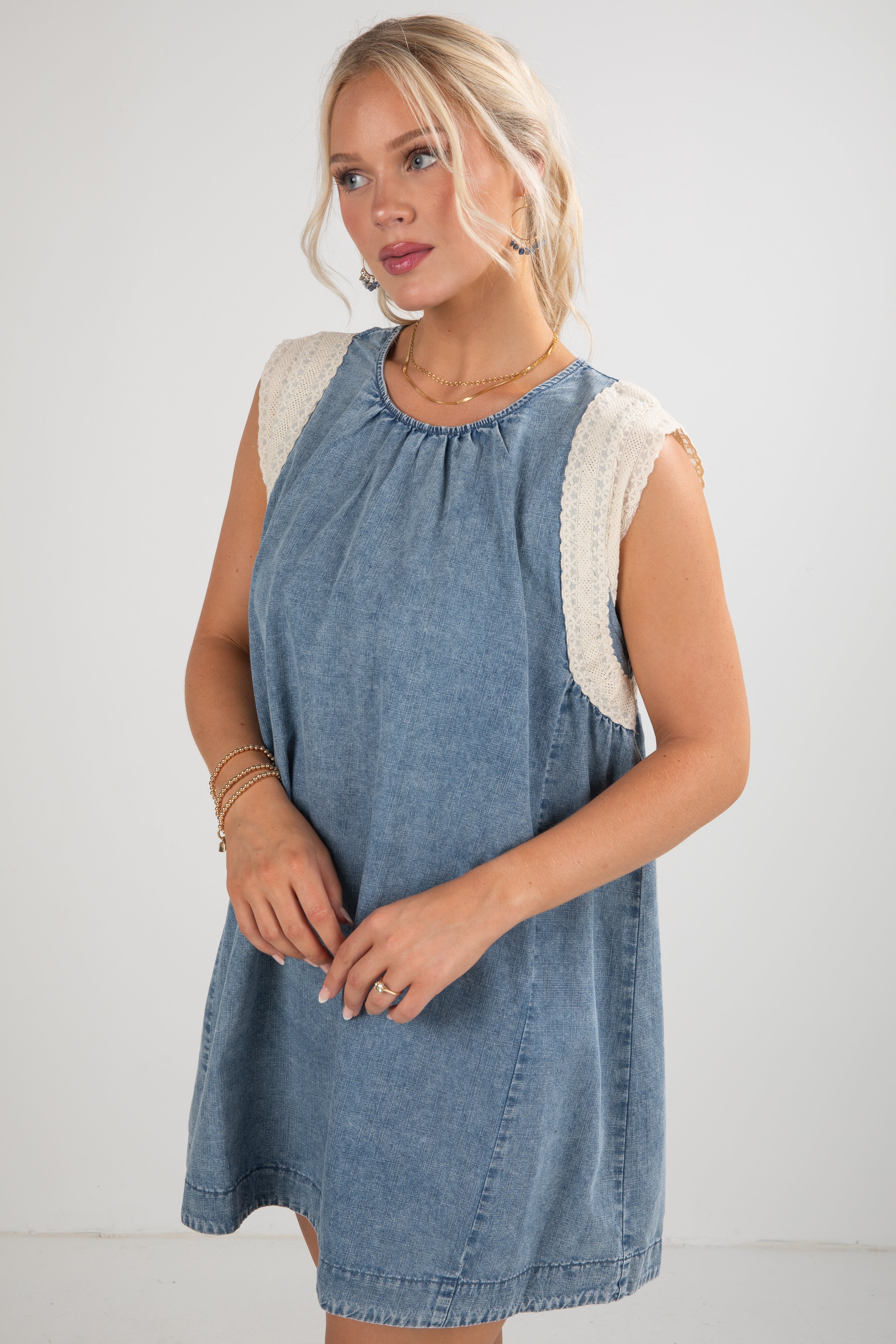 Woman wearing a denim dress with white trim against a plain background