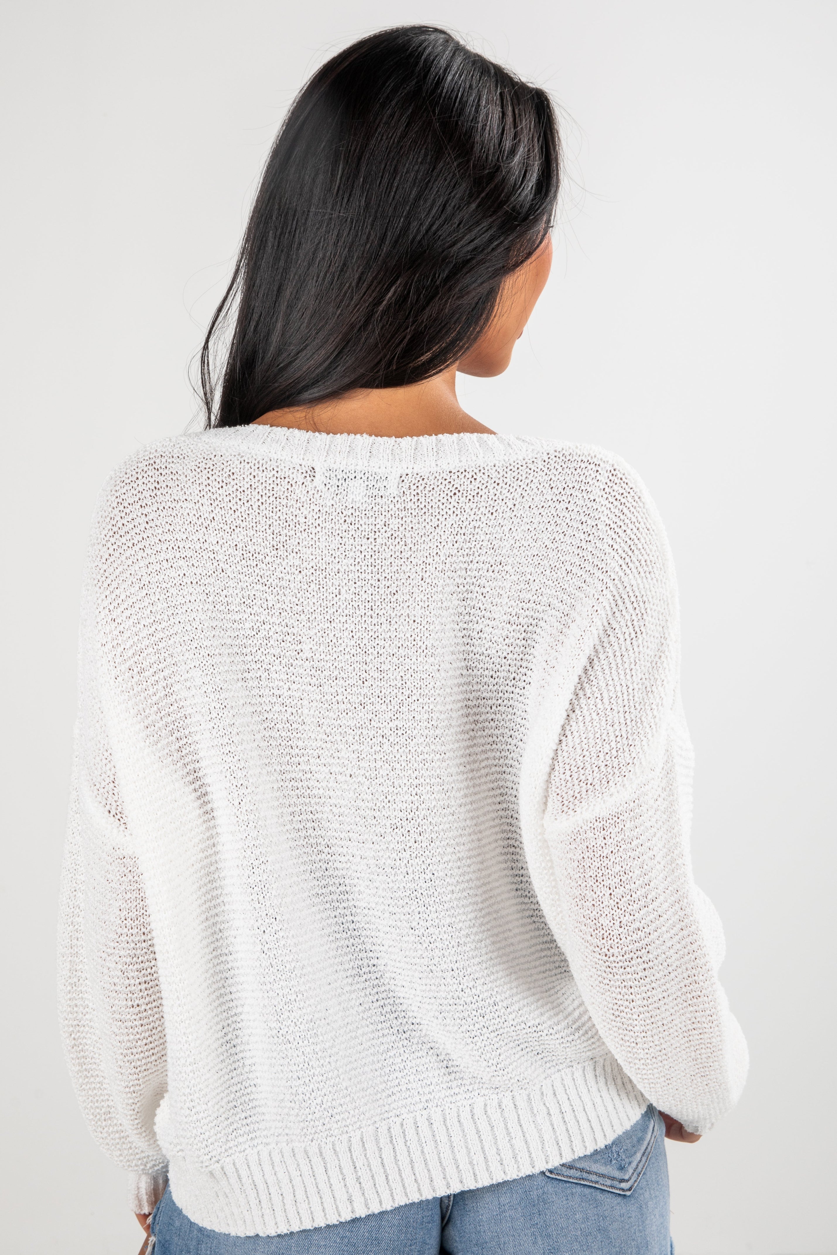Person wearing a white textured sweater on a plain background