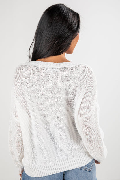 Person wearing a white textured sweater on a plain background