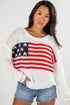 Woman wearing a white sweater with an American flag design on a plain background